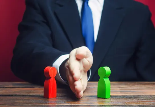 A hand reaching out to a couple of wooden figures