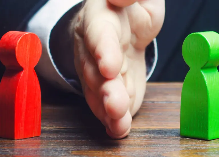 A hand reaching out to a couple of wooden figures