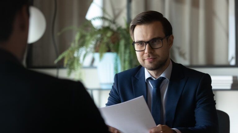 Smiling lawyer sits at a desk opposite male client